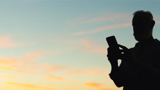 älterer Mann mit Handy in der Dämmerung