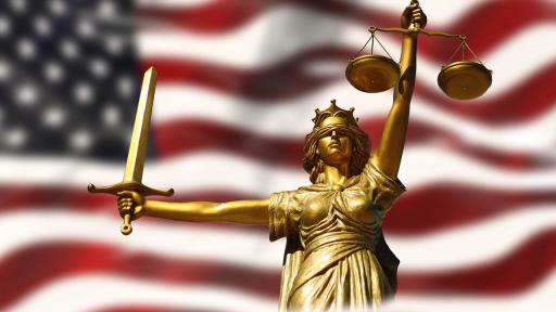 Die amerikanische Flagge mit der Figur der Justita, stellvertretend für US-Risiken, über die Referierende an der Fachtagung sprechen werden