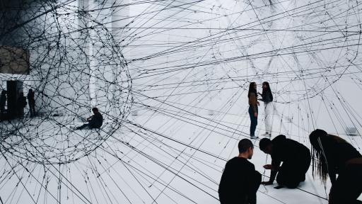 Personen sitzen in einem Netz-artigen Kunstwerk, das die Verknüpfung von finanziellen Daten symbolisiert. Foto von Alina Grubnyak (unsplash.com)